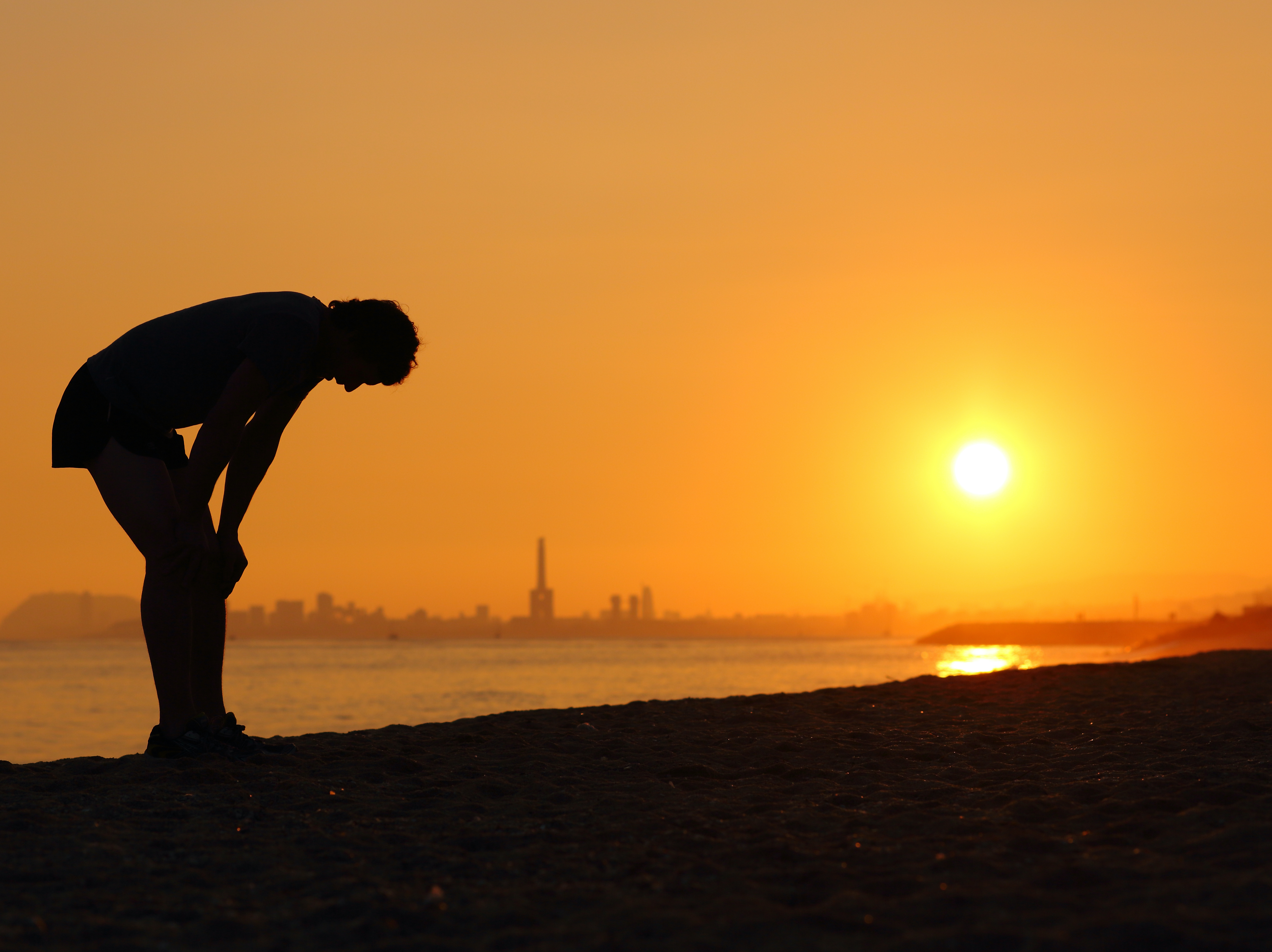 Horizon, person on beach bending over in heat