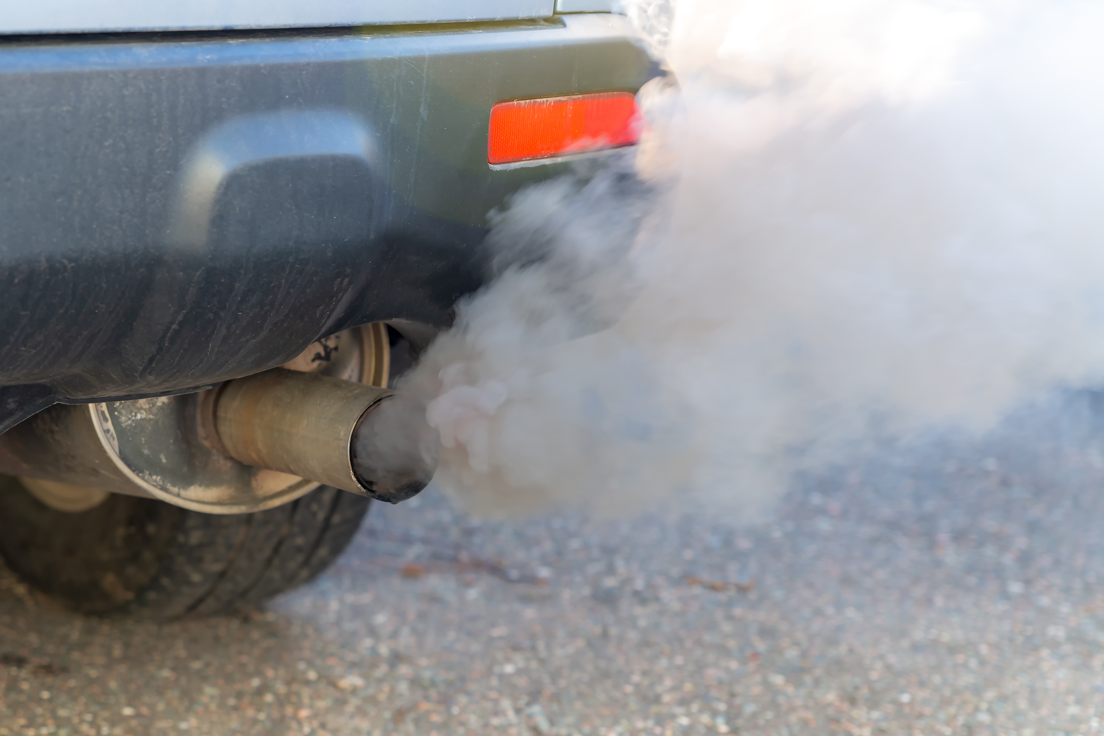 A car with grey exhaust pouring out of its tailpipe