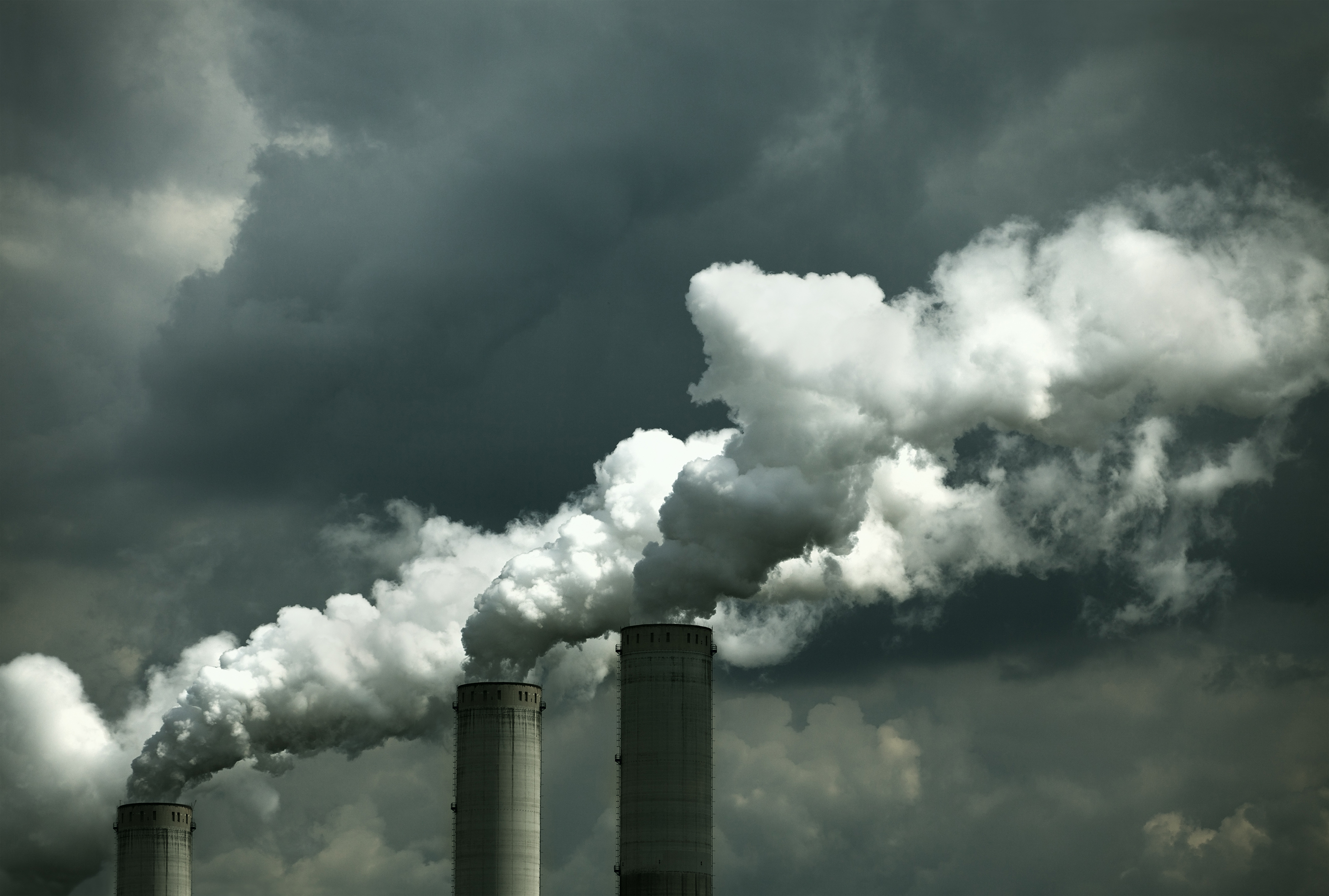 Smokestacks releasing emissions on a cloudy day.