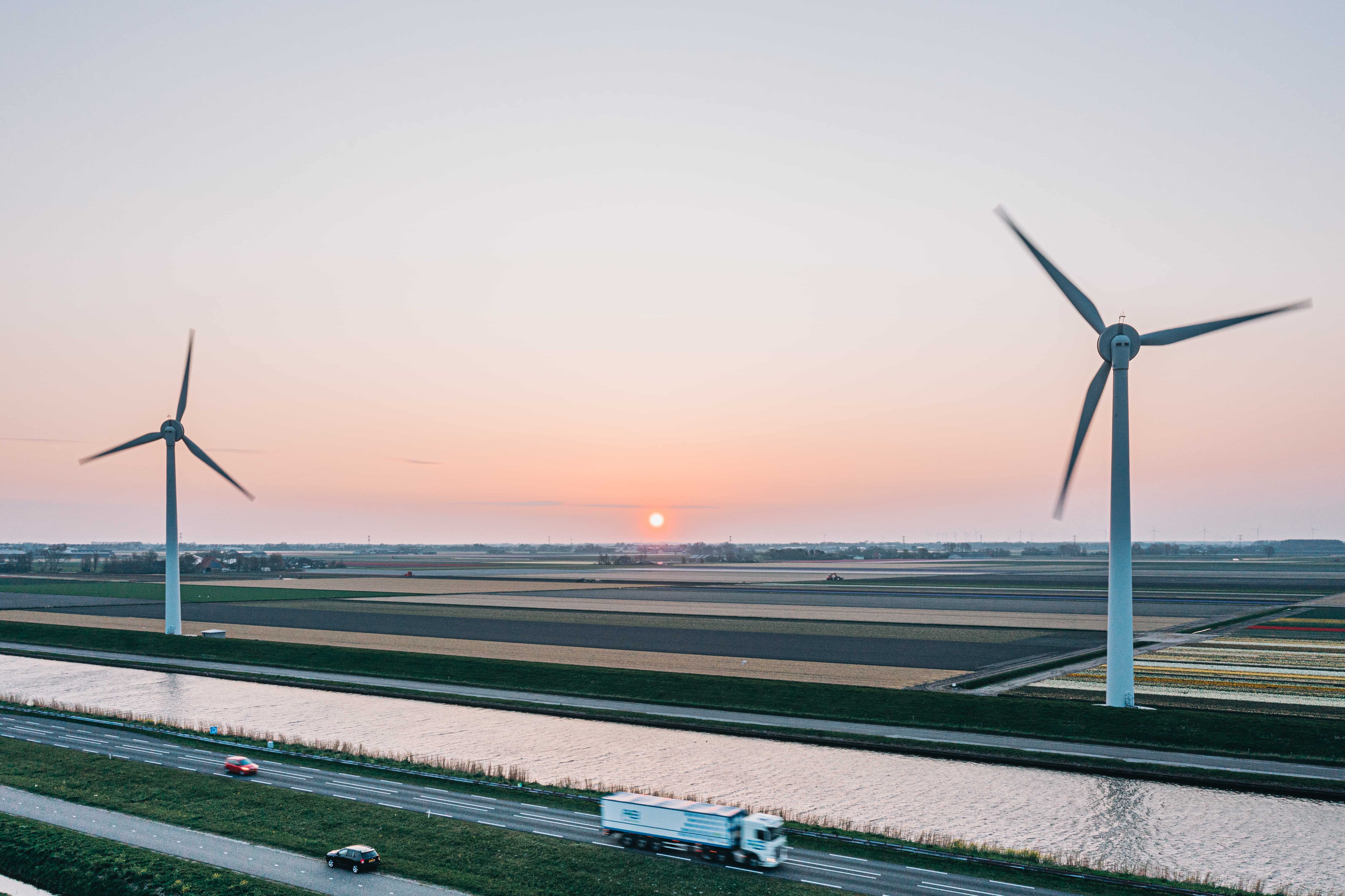 A truck driving, with wind turbines in the background.