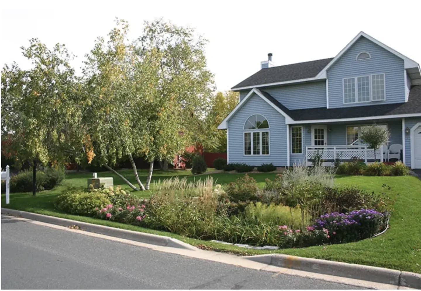 A house with a beautiful rain garden of plants and flowers outside.