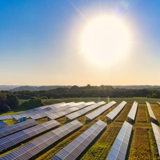 A blazing sun in the sky powers a solar panel field