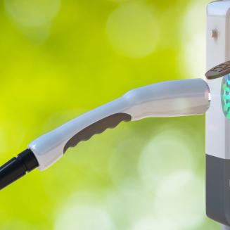 An EV charging cable about to plug into a port but it's kind of hanging in mid air like there are magnets or some invisible wizard holding it up