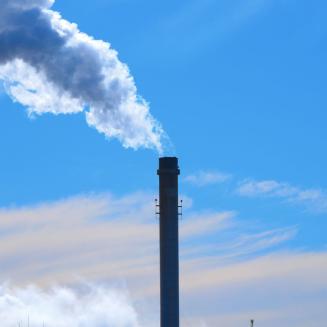 A smokestack with white smoke billowing out