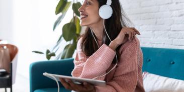 Woman on a couch listening to the Degrees podcast with headphones