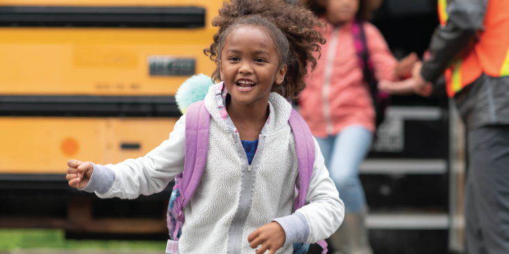 Smiling girl coming off school bus