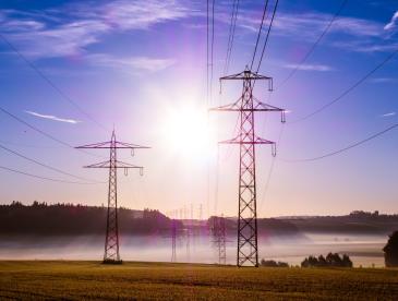 Transmission lines with beaming sun in the background