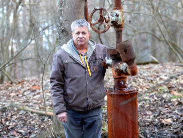 Farmer standing next to a leaking orphan well.