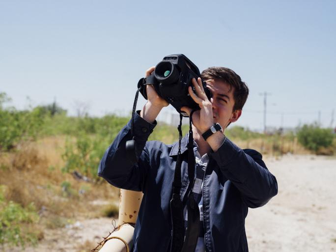 A researcher uses a handheld imaging device outdoors.