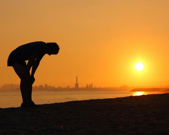 Horizon, person on beach bending over in heat