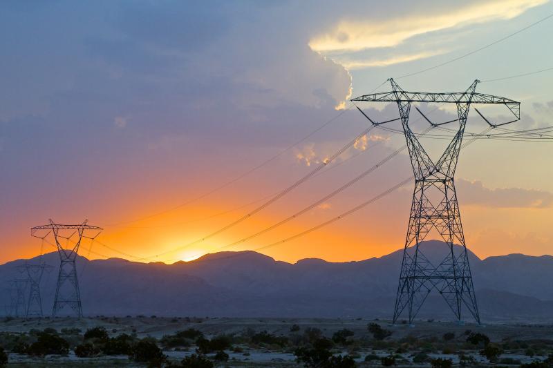 High-voltage transmission towers with sunset in the background